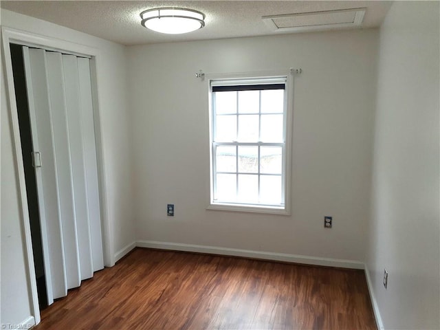 unfurnished room featuring a textured ceiling and dark hardwood / wood-style flooring