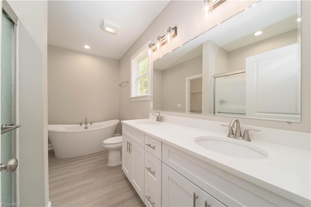 2578 Whipporwill Ct, Rural Hall, NC 27045 - bathroom with double vanity, a soaking tub, a shower with shower door, wood finished floors, and toilet