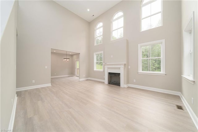 2578 Whipporwill Ct, Rural Hall, NC 27045 - unfurnished living room with a high ceiling, light wood finished floors, a fireplace, and baseboards