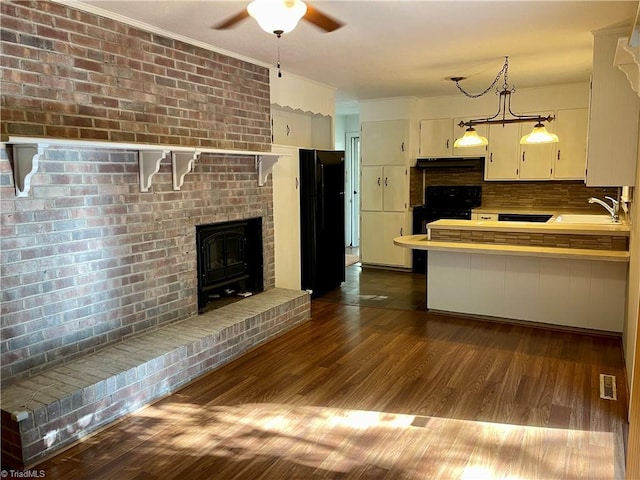 kitchen featuring pendant lighting, dark hardwood / wood-style flooring, sink, decorative backsplash, and black appliances