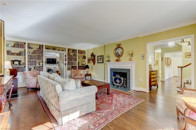 living room with built in shelves, wood-type flooring, and ornamental molding