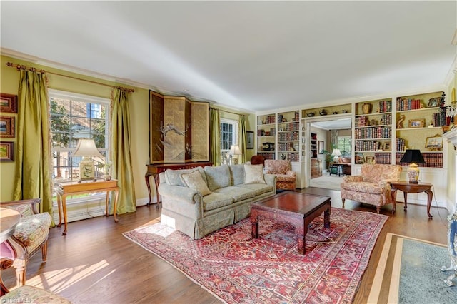 living room with a fireplace, hardwood / wood-style flooring, built in features, and ornamental molding