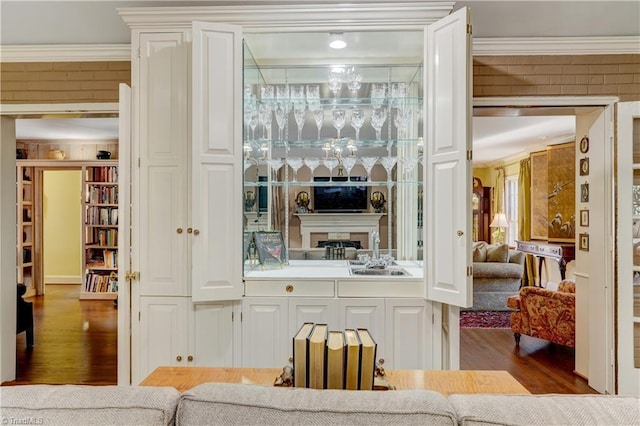 bar featuring sink, wood-type flooring, and crown molding