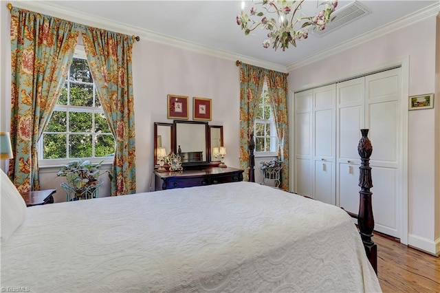 bedroom with a chandelier, light wood-type flooring, a closet, and crown molding