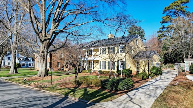 colonial inspired home featuring a balcony and a front yard