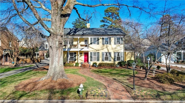 view of front of house with a balcony and a front yard