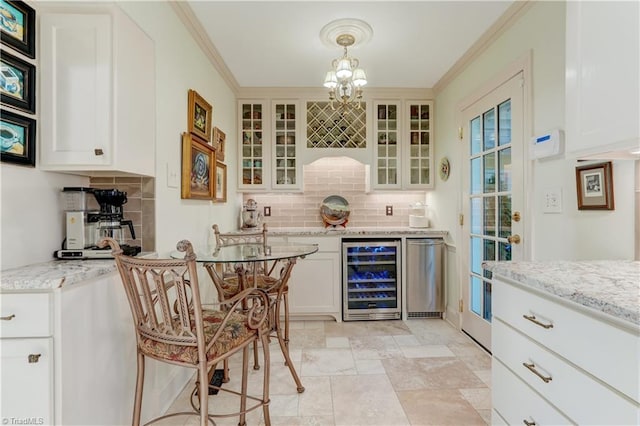 bar featuring decorative light fixtures, white cabinetry, ornamental molding, and beverage cooler