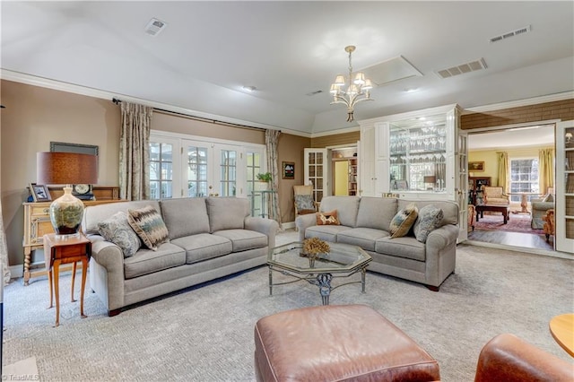 carpeted living room featuring a chandelier, french doors, and vaulted ceiling