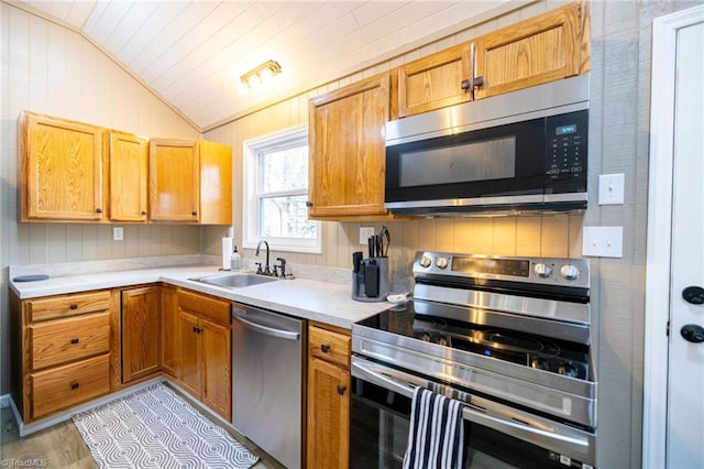 kitchen featuring a sink, vaulted ceiling, light countertops, and stainless steel appliances