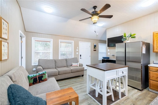 living area with lofted ceiling, light wood-style flooring, and a ceiling fan