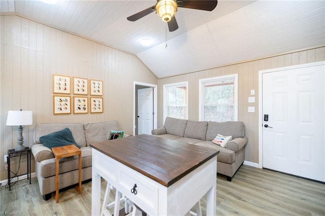 living area featuring light wood-style flooring, baseboards, lofted ceiling, and ceiling fan