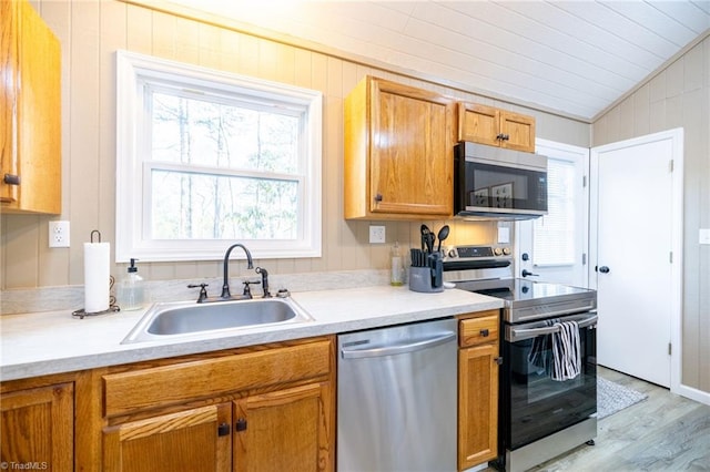 kitchen featuring a sink, lofted ceiling, appliances with stainless steel finishes, and light countertops