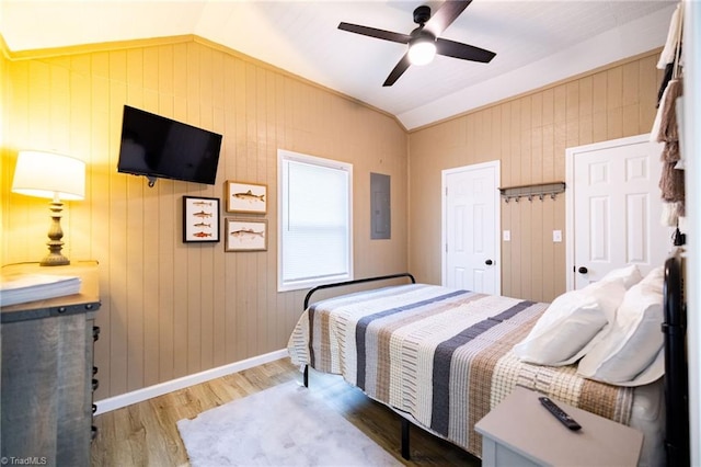 bedroom featuring ceiling fan, baseboards, lofted ceiling, electric panel, and wood finished floors