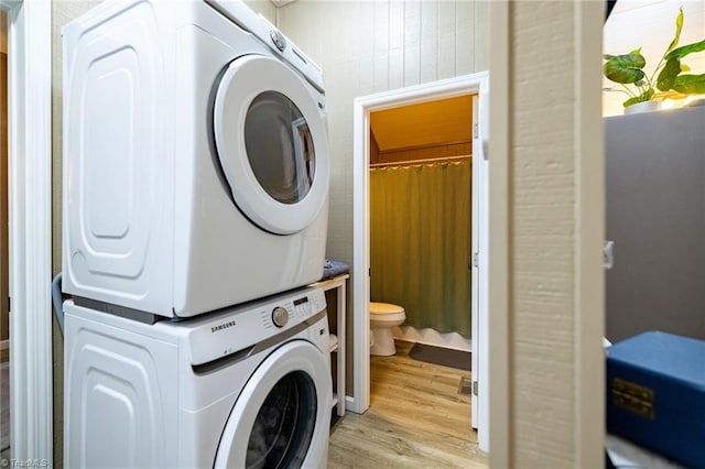 laundry area featuring laundry area, light wood-style flooring, and stacked washing maching and dryer