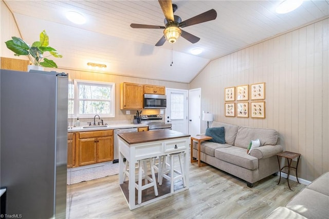 kitchen featuring a sink, lofted ceiling, appliances with stainless steel finishes, and light wood-style flooring