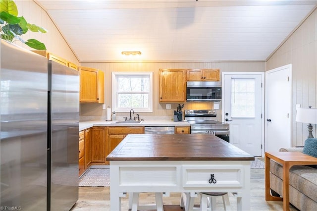 kitchen featuring lofted ceiling, light wood-style flooring, a sink, appliances with stainless steel finishes, and wood counters