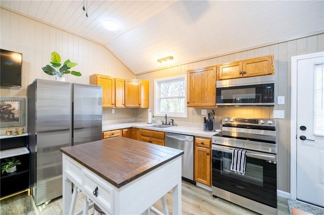 kitchen with light wood-style flooring, a sink, vaulted ceiling, wood ceiling, and appliances with stainless steel finishes