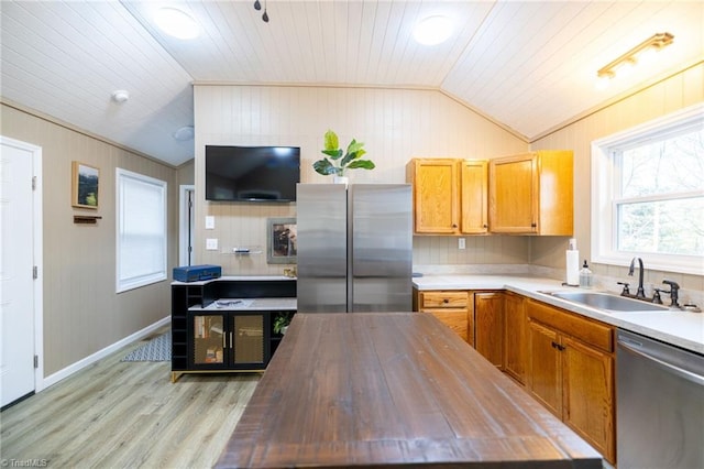 kitchen with a sink, wood counters, stainless steel appliances, light wood finished floors, and vaulted ceiling