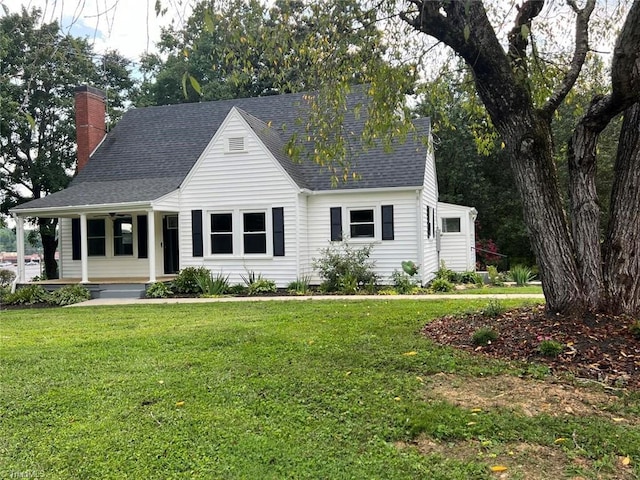 cape cod-style house featuring covered porch, a chimney, a front yard, and roof with shingles