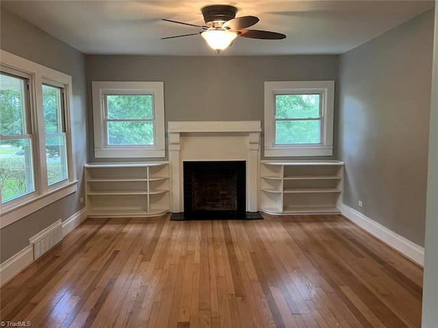 unfurnished living room featuring a wealth of natural light, visible vents, and hardwood / wood-style flooring