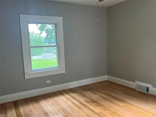 empty room with visible vents, a ceiling fan, light wood-type flooring, and baseboards