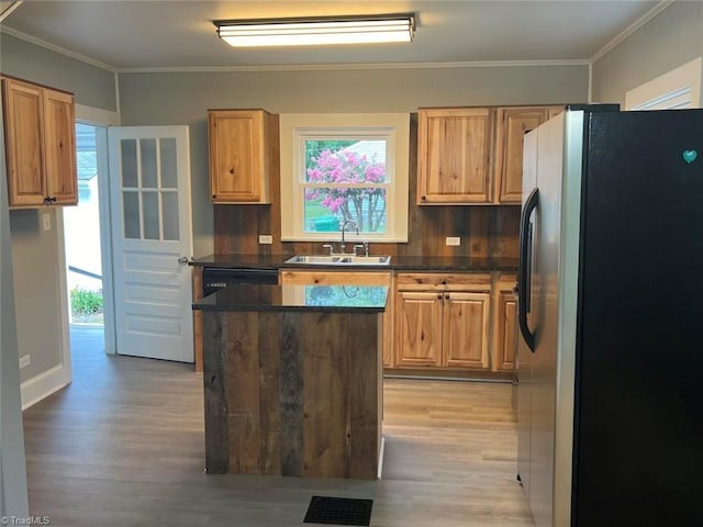 kitchen with visible vents, freestanding refrigerator, a sink, crown molding, and a center island