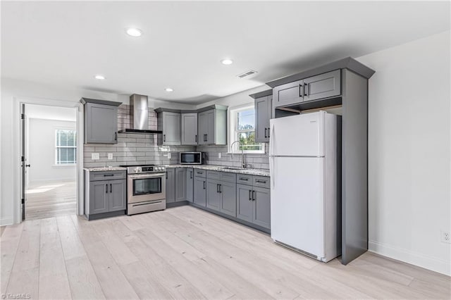 kitchen featuring wall chimney exhaust hood, sink, light wood-type flooring, gray cabinets, and stainless steel appliances