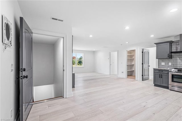 kitchen with gray cabinets, stainless steel electric stove, tasteful backsplash, and light hardwood / wood-style flooring