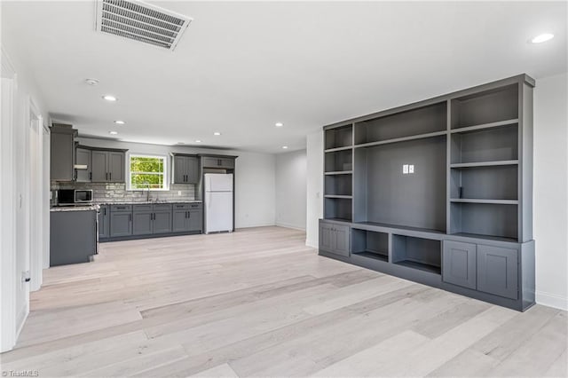 unfurnished living room featuring light wood-type flooring and sink