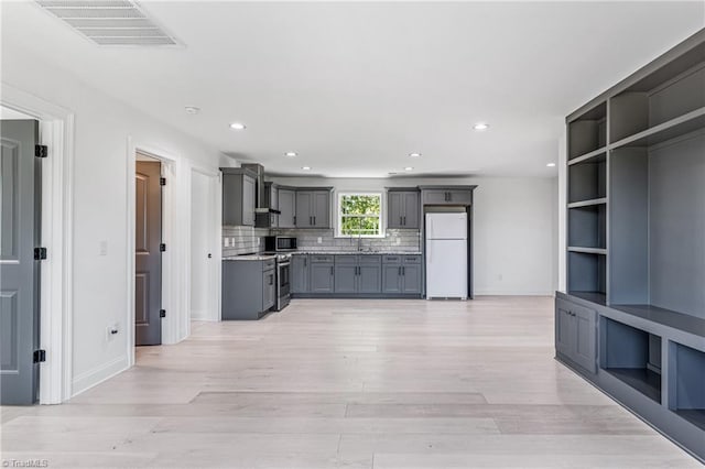 kitchen with sink, backsplash, gray cabinets, wall chimney range hood, and stainless steel appliances