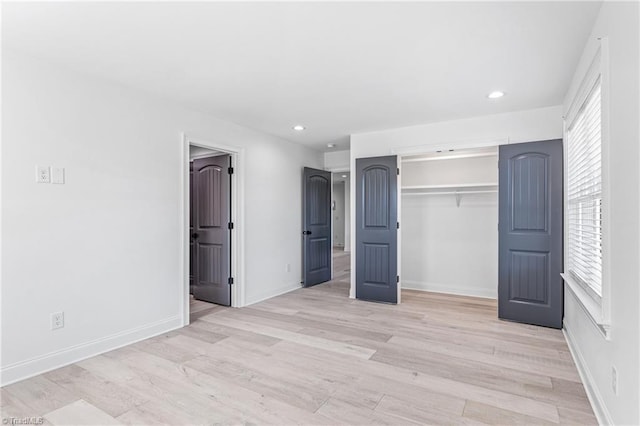 unfurnished bedroom featuring multiple windows, a closet, and light hardwood / wood-style flooring