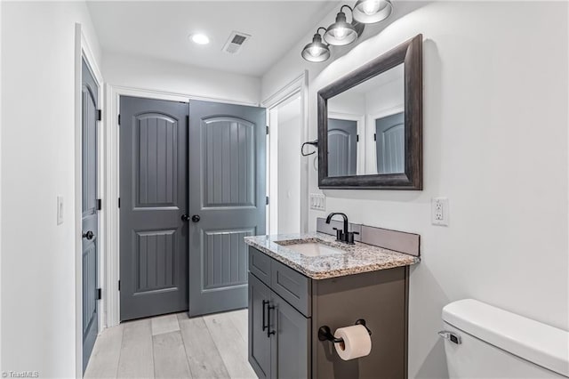 bathroom with hardwood / wood-style flooring, toilet, and vanity