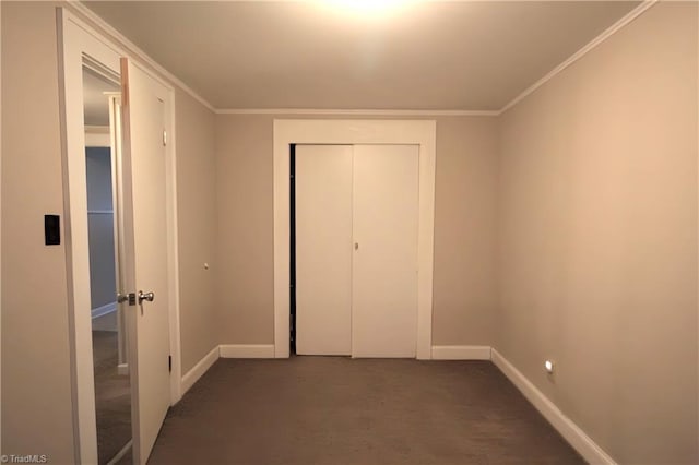 unfurnished bedroom with baseboards, ornamental molding, a closet, and dark carpet