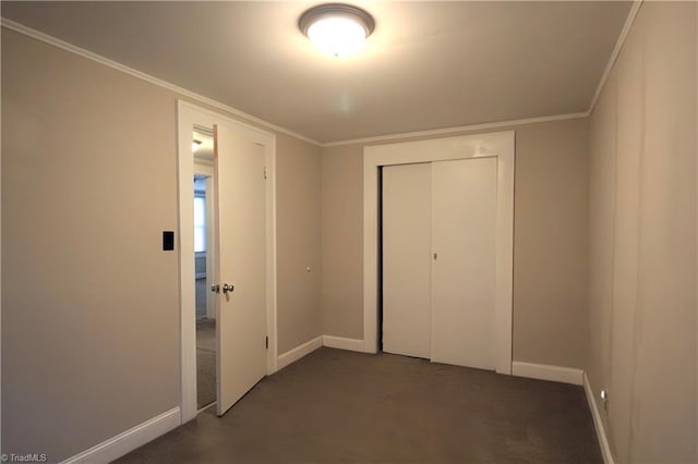unfurnished bedroom featuring a closet, baseboards, ornamental molding, and dark colored carpet