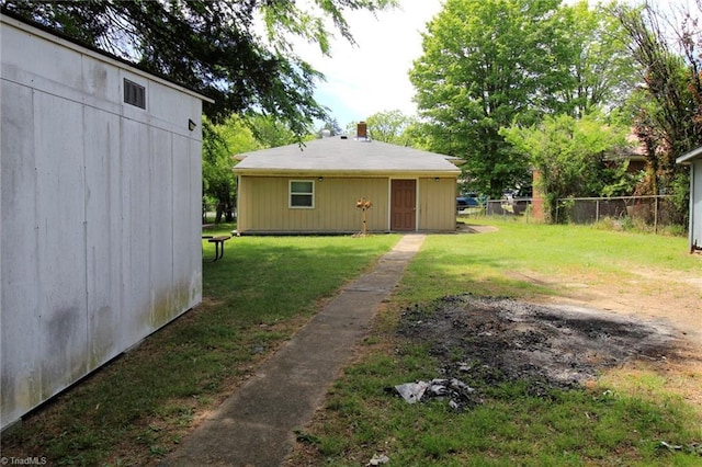 rear view of property featuring fence, a chimney, and a lawn