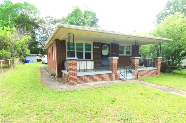 bungalow with covered porch, brick siding, fence, and a front yard