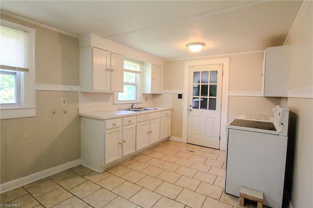 kitchen with light tile patterned flooring, a sink, washer / clothes dryer, white cabinetry, and baseboards