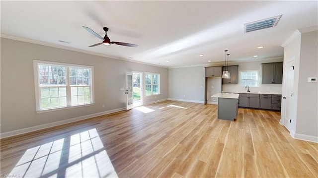 3043 Loch Dr, Winston-Salem, NC 27106 - unfurnished living room featuring crown molding, a ceiling fan, baseboards, light wood-style flooring, and a sink