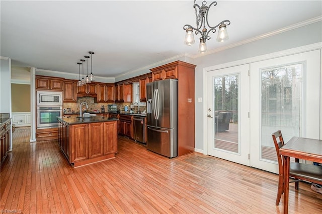 kitchen with brown cabinetry, stainless steel appliances, and crown molding