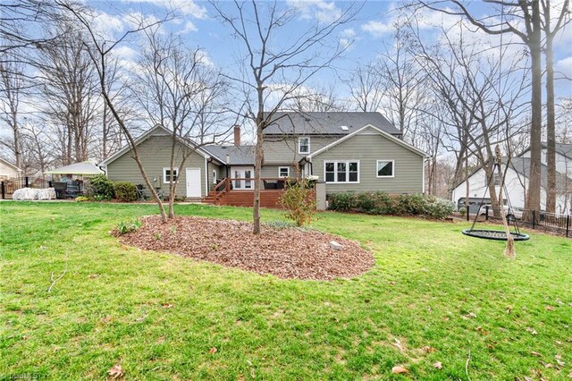 rear view of property with a lawn and fence