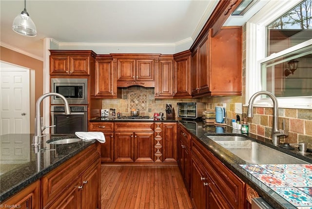 kitchen featuring dark wood finished floors, decorative light fixtures, appliances with stainless steel finishes, and a sink