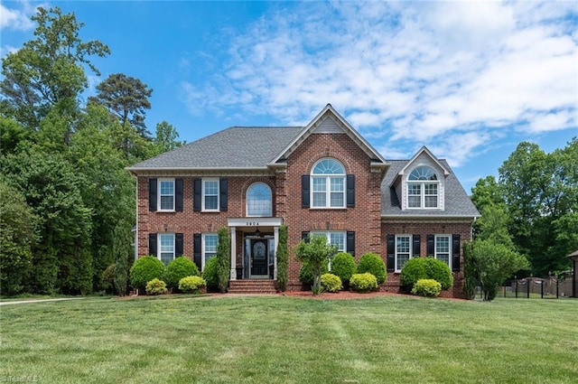view of front of home featuring brick siding, a front lawn, and fence