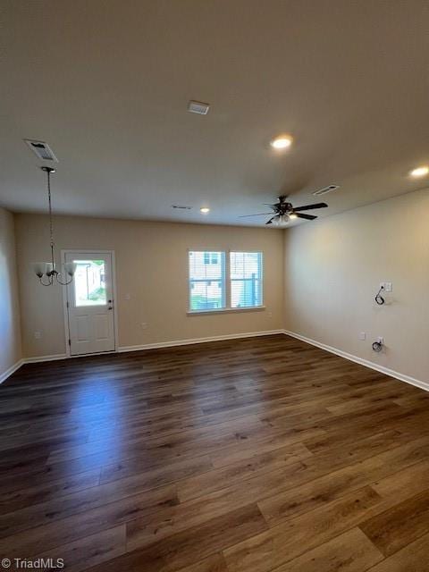 empty room with ceiling fan with notable chandelier and dark hardwood / wood-style flooring