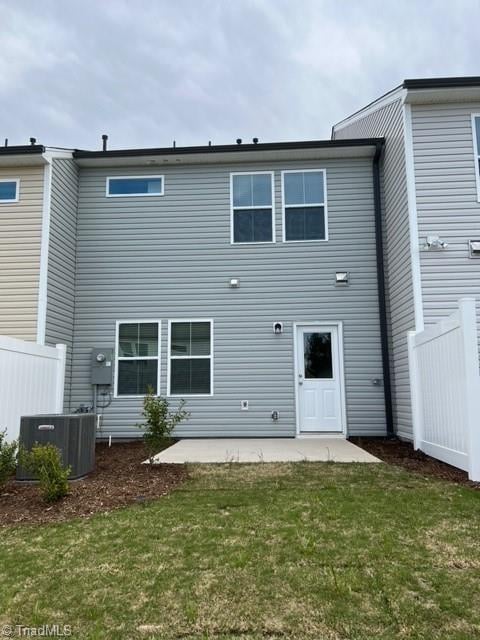 back of property with cooling unit, a lawn, and a patio area