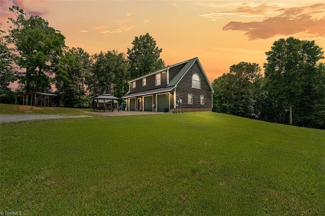 924 Delta Dr, Randleman, NC 27317 - back of house at dusk with a gazebo, driveway, an attached garage, a lawn, and view of scattered trees