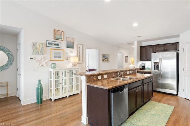 kitchen with a sink, light wood finished floors, appliances with stainless steel finishes, and dark brown cabinets