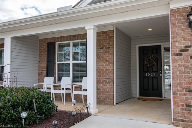 property entrance featuring a porch and brick siding