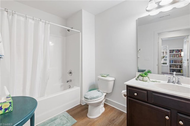 bathroom with baseboards, toilet, shower / tub combo, wood finished floors, and vanity