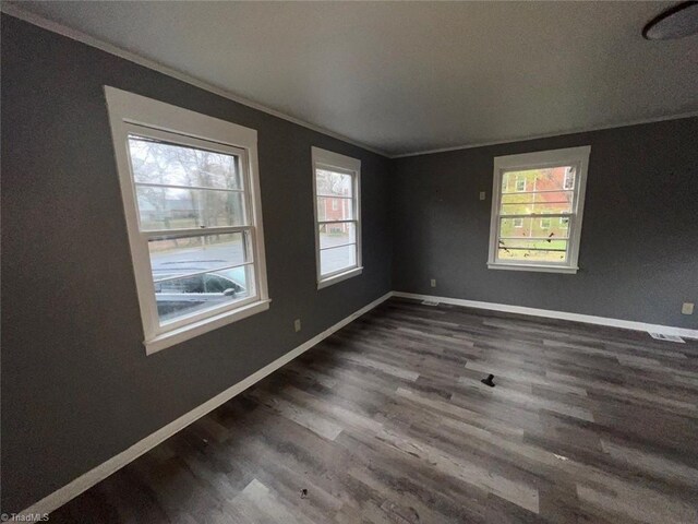 spare room featuring dark wood-style flooring, baseboards, and ornamental molding