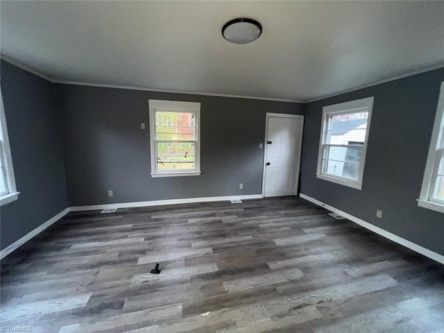 empty room with crown molding, plenty of natural light, and wood finished floors